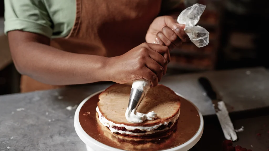 A person squeezes icing to decorate a cake