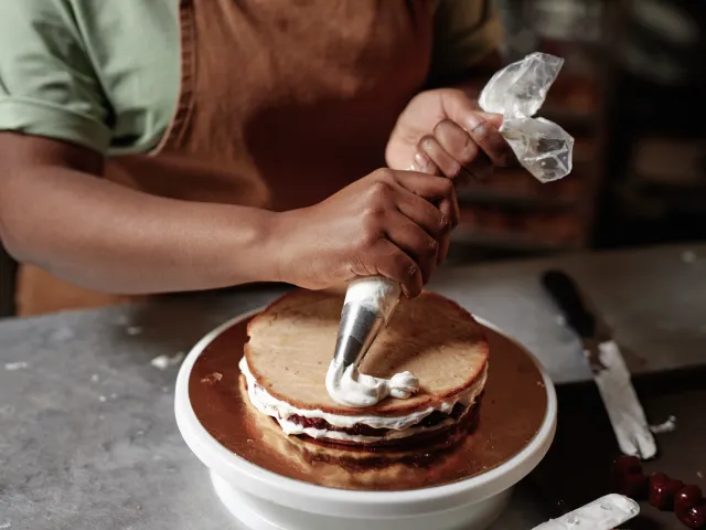 A person squeezes icing to decorate a cake