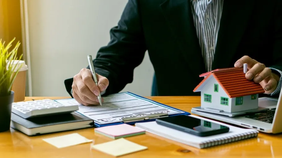 real estate agent at a computer with a small model home next to it