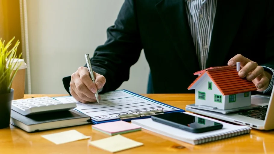 real estate agent at a computer with a small model home next to it