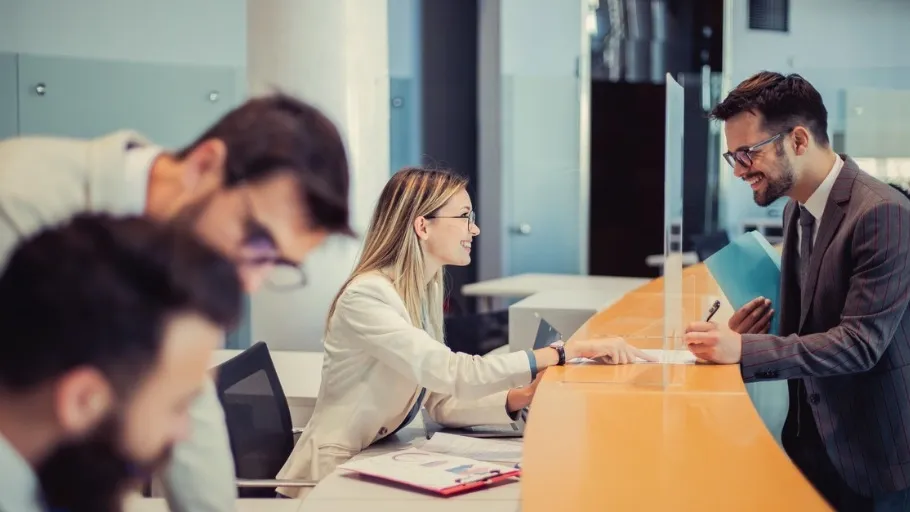 Man at bank teller counter talking to bank employee