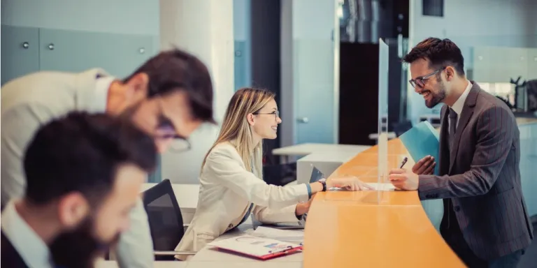 Man at bank teller counter talking to bank employee