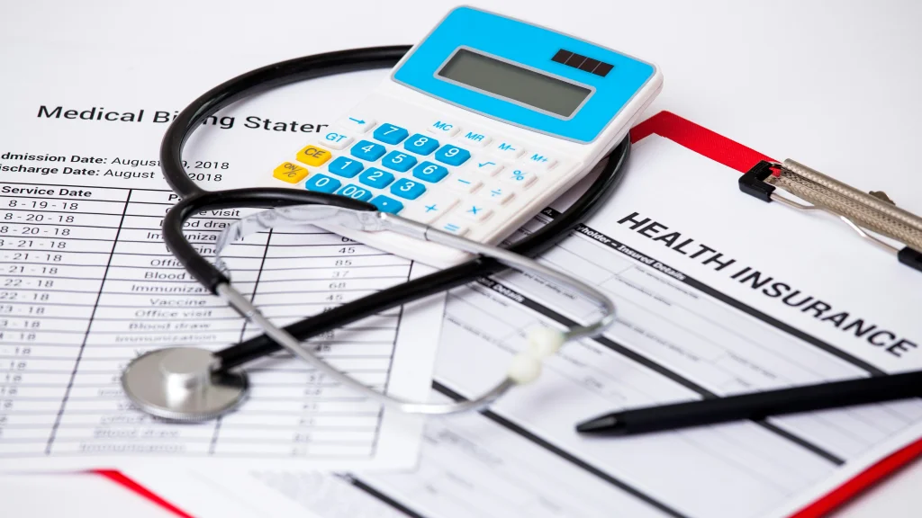 a desktop with a stethoscope, health insurance form and calculator