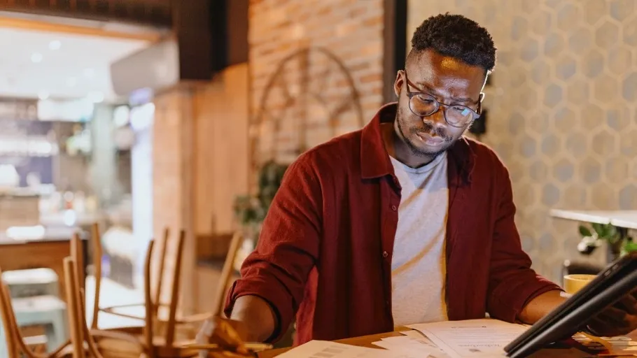 Male coffee shop owner sitting at table working through quarterly taxes