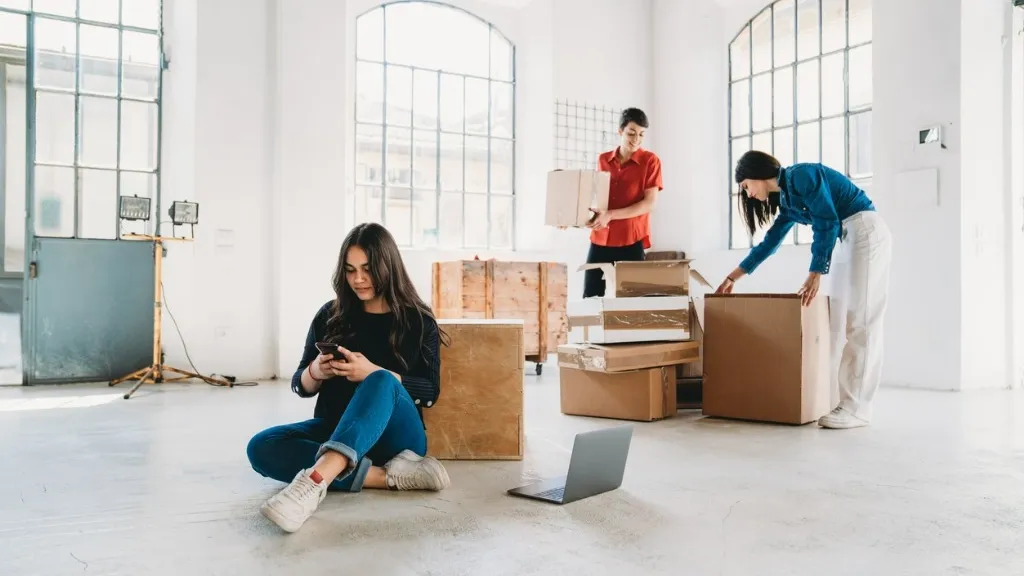 A group of small business owners unpacks boxes while one starts an llc