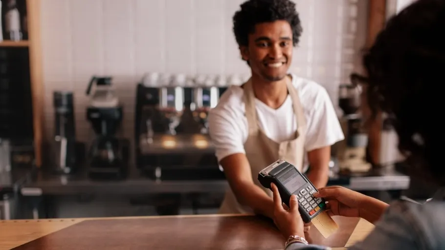 A young business owner accepts a credit card payment on a POS provided by a credit card processing company.