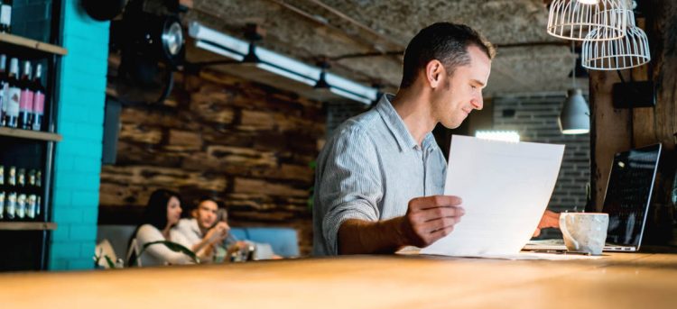 Male business owner working at a restaurant doing the books - entrepreneurship concepts